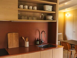 A compact kitchen with a wooden countertop, a sink, and a dining area with a chair.