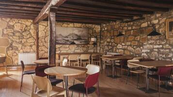 A rustic interior with stone walls, wooden tables, and chairs.
