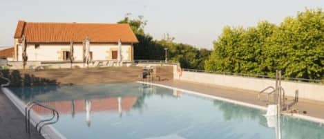 A swimming pool with a clear view of a building with a red roof in the background.