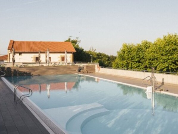 A swimming pool with a clear view of a building with a red roof in the background.