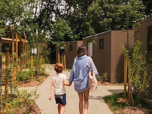 A pathway between buildings with greenery and a clear sky.