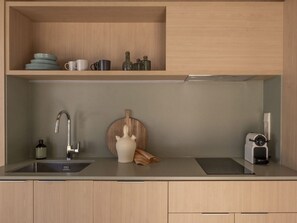 A modern kitchen with a stainless steel sink, a wooden cutting board, and a coffee machine.