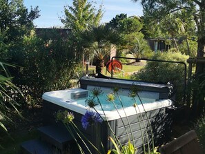 A hot tub surrounded by lush greenery and a wooden fence. - Mobile home with AC, comfortable - 6 guests (Saint-Jean-de-Monts)