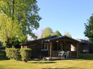 Une cabane en bois avec une véranda, deux tables et des chaises.