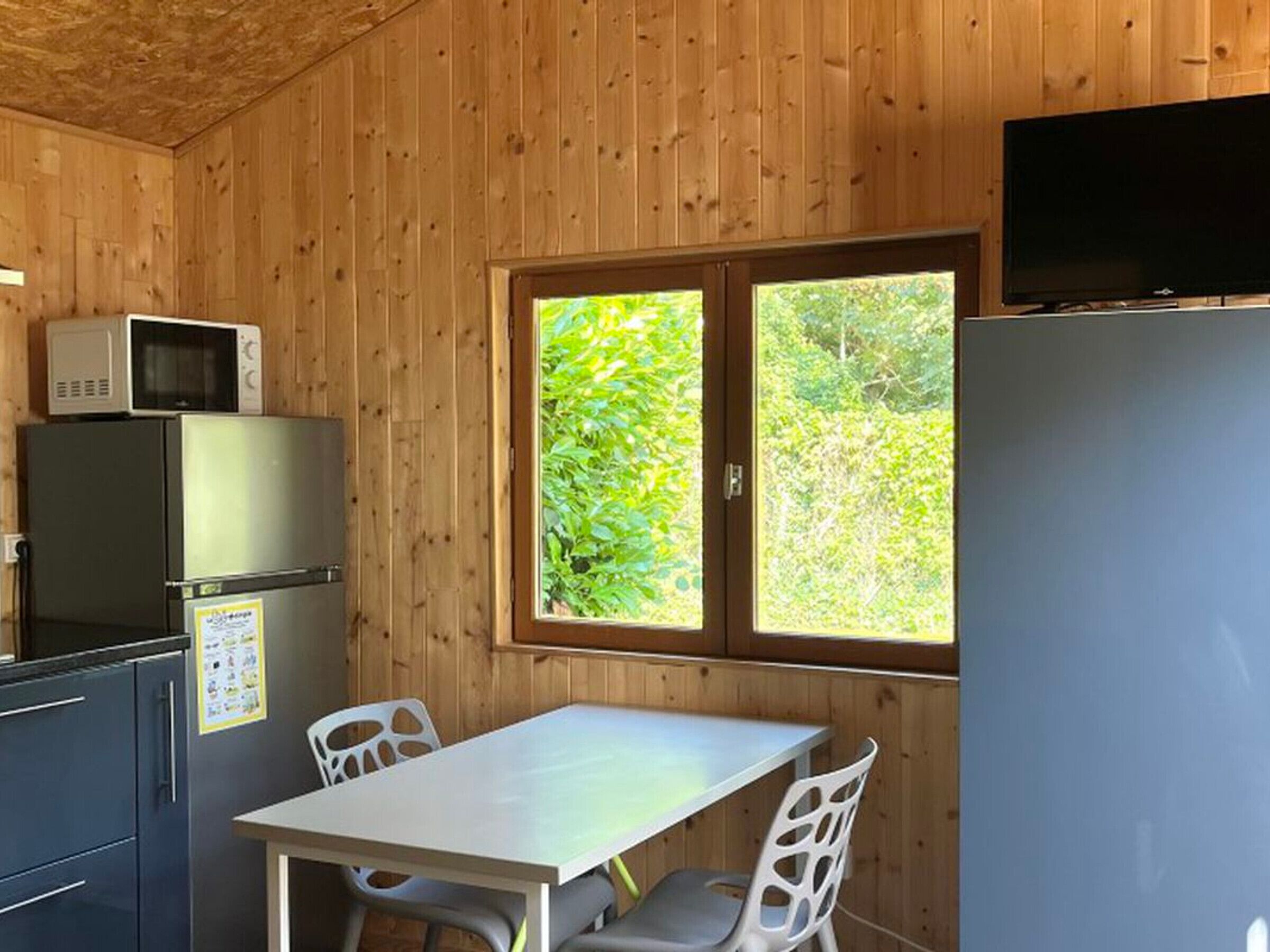 L’intérieur d’un chalet en bois comprend un coin cuisine équipé d’un réfrigérateur, d’un four à micro-ondes et d’une table avec des chaises.