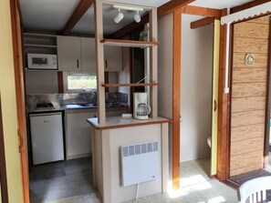 Una kitchenette compacta equipada con microondas, cafetera y un refrigerador pequeño.