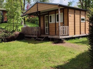 A small wooden cabin with a porch, a door, and a window. - Chalet pets allowed - 5 guests (La Tour-d'Auvergne)