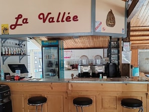 A bar area with a sign reading 'La Vallée,' a refrigerated display case, and a counter with stools. - Chalet pets allowed - 5 guests (La Tour-d'Auvergne)