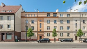 En rad med flerfamiljshus, följt av en rad parkerade bilar, en gatlykta och en skylt för ett vandrarhem.