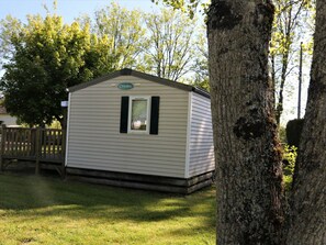 A small, single-story mobile home with a gabled roof, a window with shutters, and a nameplate on the front. - Mobile home pets welcome - 6 guests (Pleaux)