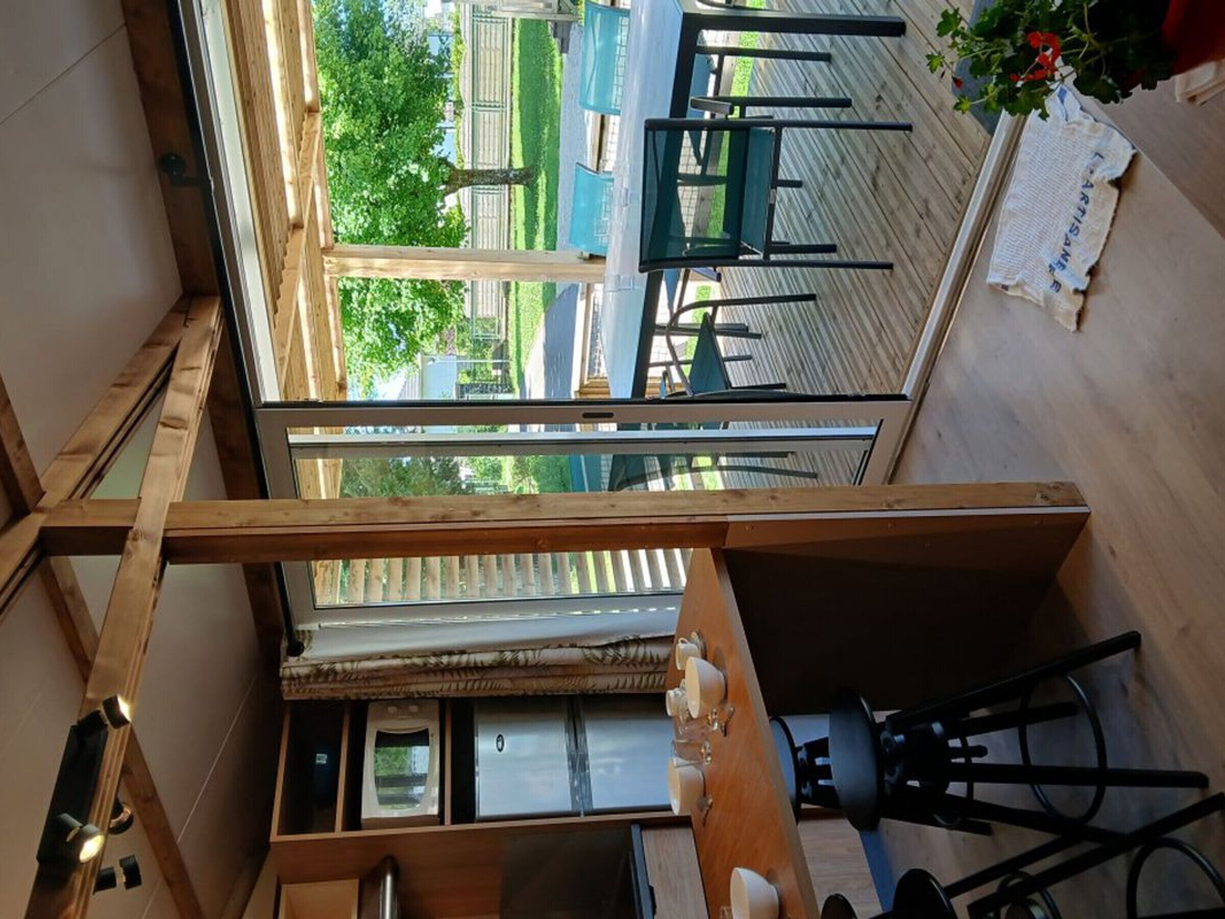 Une pièce avec vue sur la rue, un coin repas avec des chaises et une table, et une kitchenette équipée d’appareils électroménagers.