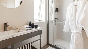 A modern bathroom with a glass-enclosed shower, a marble sink, and a white bathrobe hanging on a rack. - Bungalow with AC, pets allowed - 4 guests (Linguizzetta)