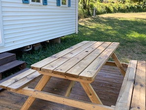 A wooden picnic table with benches, set on a wooden deck.