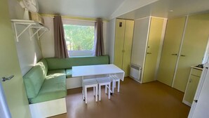 Pieni huone, jossa on vihreä sohva, pieni pöytä, ikkuna, jossa on verhot, ja patteri.