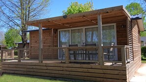 En stuga byggd av trä med en inglasad veranda, stora fönster och ett inhägnat utomhusområde.