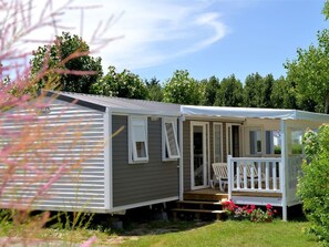 Ein Wohnmobil mit Veranda, einem Stuhl und einem kleinen Garten.