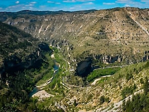 Een bergachtig landschap met een kronkelende rivier en een weg.