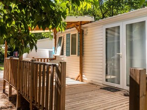 A mobile home with a deck, a covered patio, and a sliding glass door. - Mobile home, pets welcome - 6 guests (Joyeuse)