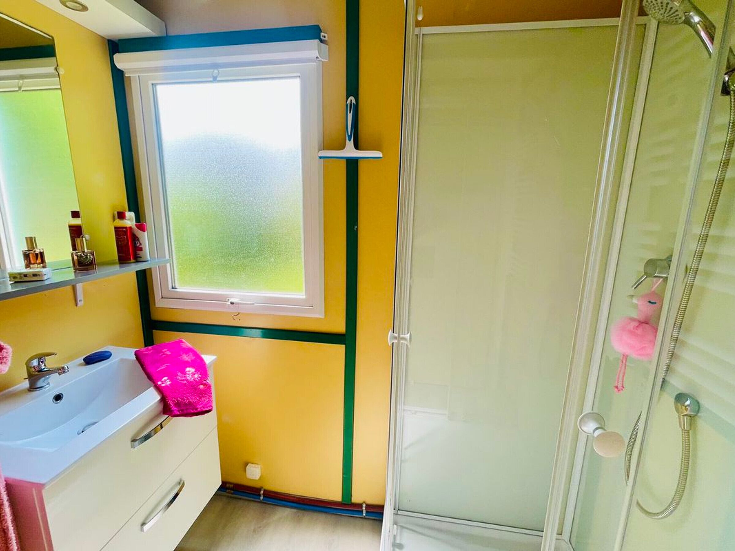 A bathroom with a window, a shower, and a sink.