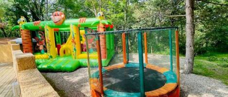 Un parque infantil con un trampolín y estructuras de juego hinchables.