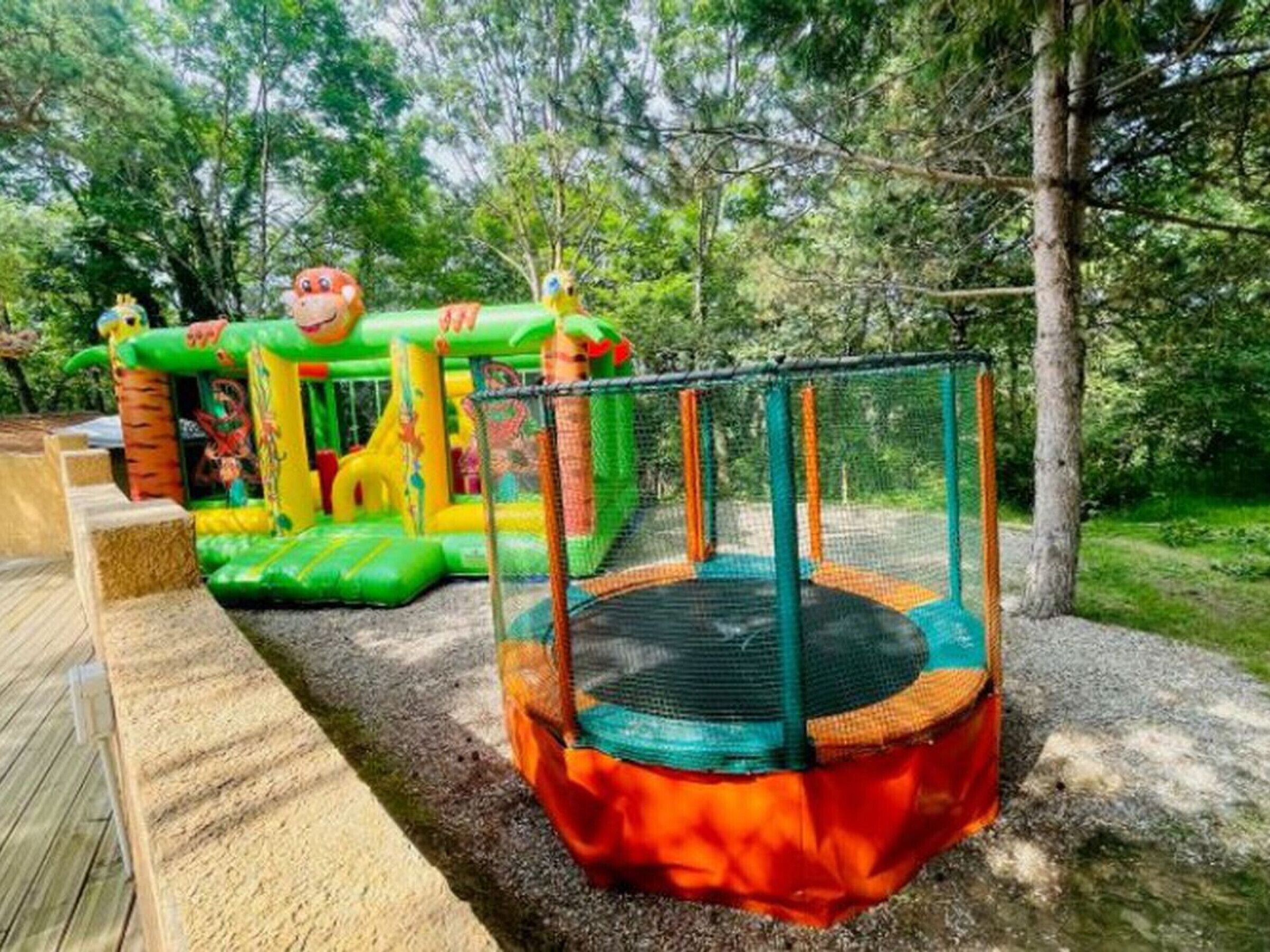 A playground with a trampoline and inflatable play structures.