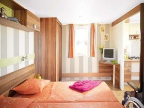 A bedroom with a bed, a desk, a chair, and a wheelchair. - Mobile home pets allowed - 1 guest (Saint-Cirq-Lapopie)
