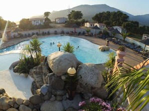 A pool with rocks and plants, lounge chairs, and a mountainous backdrop. - Mobile home with AC - 6 guests (Propriano)