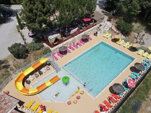En swimmingpool med vandrutsjebane, liggestole og et overdækket siddeområde.