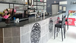 Una zona de bar con estantes llenos de vasos y botellas, un reloj y un logotipo en la barra.
