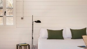 A bedroom with a bed, two pillows, a nightstand, a lamp, and a window. - Cabin with AC - 2 guests (Las Negras)