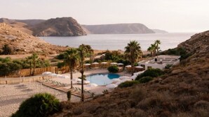 A resort with a pool, palm trees, and a view of the sea and mountains. - Cabin with AC - 2 guests (Las Negras)