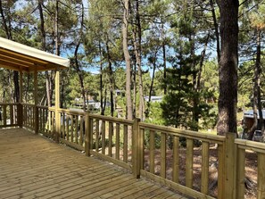 Eine Holzterrasse mit Geländer, mit Blick auf ein bewaldetes Gebiet.