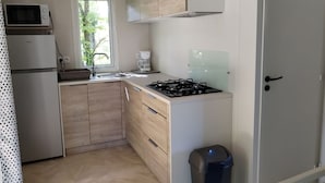 A compact kitchen with a microwave, stove, sink, and cabinets. - Mobile home, pets welcome - 4 guests (Chaillé-les-Marais)
