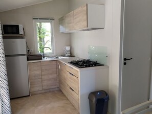 A compact kitchen with a microwave, stove, sink, and cabinets. - Mobile home, pets welcome - 4 guests (Chaillé-les-Marais)