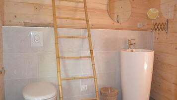 A bathroom with a toilet, sink, mirror, and a wooden ladder.