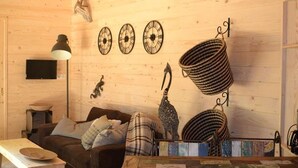A cozy cabin interior with a wooden wall, a hanging lamp, a couch, a flat-screen TV, and a wall clock. - Chalet with disabled access - 6 guests (Magné)
