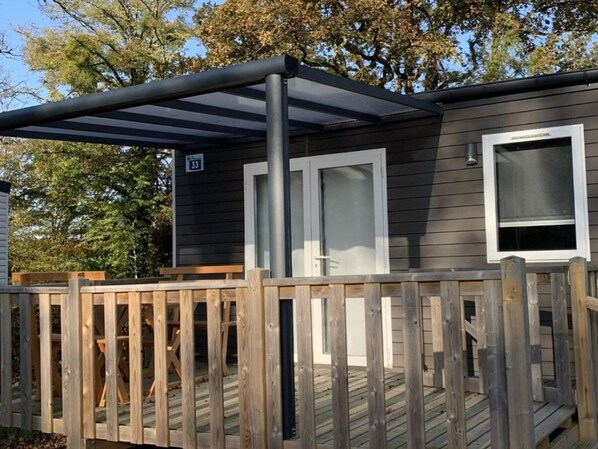 A small cabin with a deck, a door, and a window. - Cozy mobile home, pets welcome - 2 guests (Arrigny)