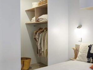 A bedroom with a bed, a nightstand, a lamp, a closet, and a wall-mounted shelf. - Mobile home with AC - 6 guests (Monplaisant)