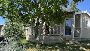 A single-story house with a porch, a visible window, and a tree in the foreground. - Chalet pets welcome - 5 guests (Saint-Georges-de-Luzençon)