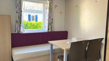 Ein Zimmer mit Fenster, einer Bank, einem Tisch und zwei Stühlen.