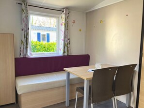 Une pièce avec une fenêtre, un banc, une table et deux chaises.