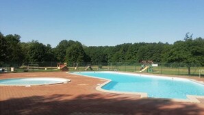 A swimming pool with a fenced area, a small building, and trees in the background. - Cozy mobile home, pets allowed - 5 guests (Sauxillanges)