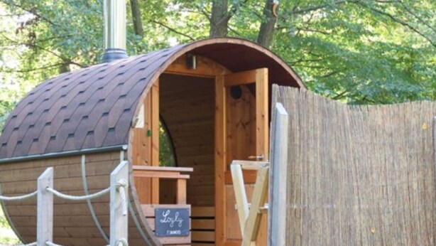A wooden cabin with a curved roof, a wooden door, and a small table and chair inside. - Cozy mobile home, pets allowed - 5 guests (Sauxillanges)