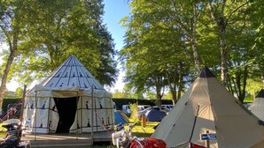 A tent with a conical roof, a motorcycle parked in front, and another tent with a pyramid-like structure. - Cozy mobile home, pets allowed - 5 guests (Sauxillanges)