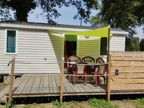 A small, single-story mobile home with a porch area featuring a table and chairs. - Cozy mobile home, pets allowed - 5 guests (Sauxillanges)