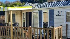 En liten, envåningsbyggnad med en veranda, en terrass och bokstaven ”L” på sidan.