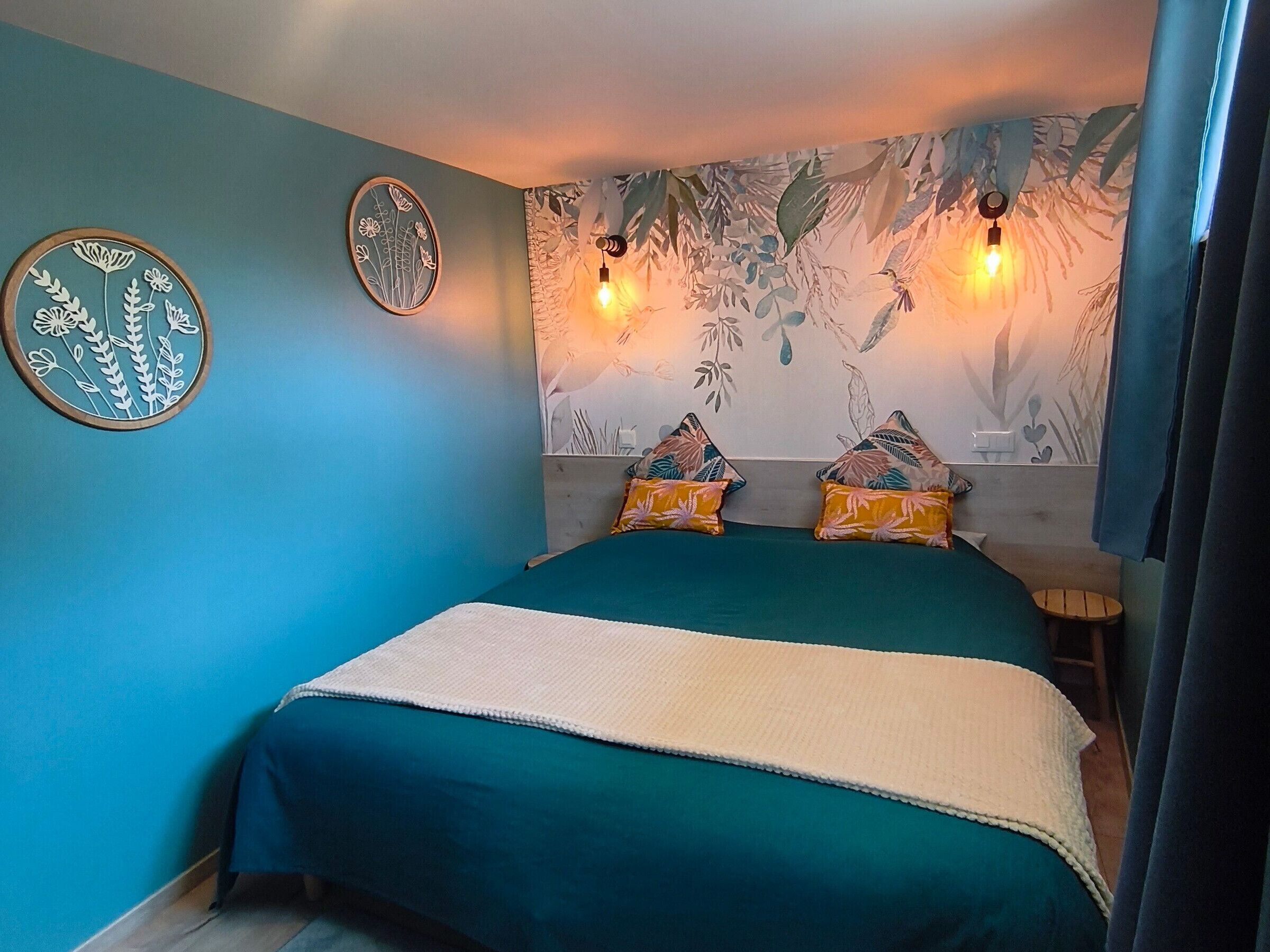 A bedroom with a bed, two wall-mounted lights, and a wall mural.