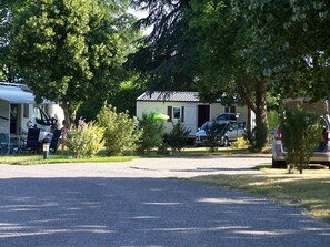 En campingplats med en grusuppfart, ett husvagn och en parkerad bil i närheten.