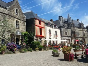 A historic stone building with a red facade, a cobblestone courtyard, and outdoor seating areas.