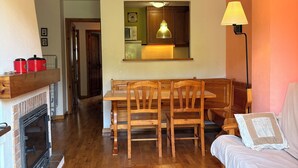 A living room with a fireplace, wooden furniture, a dining area, and a kitchen in the background. - Mountain environment. Fireplace and garden - Isard 4 (Pla de l'Ermita)